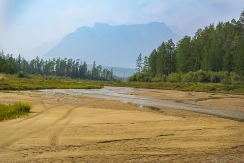 River flowing through sandy valley with mountain backdrop Stock Photos