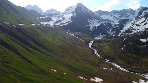 River flowing through snowy mountains in spring 4k aerial footage Stock Footage 294735078