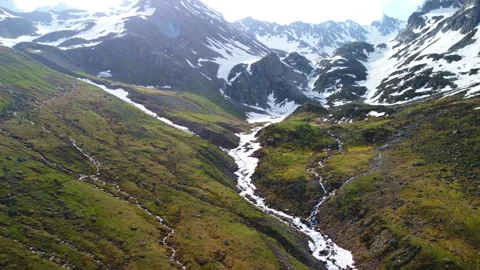 River flowing through snowy mountains in spring 4k aerial footage Video stock 294740603