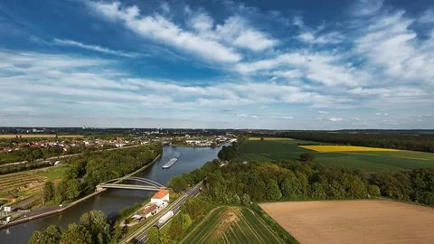 A river flowing through trees and fields, seen from above under a cloudy sky Stock Photos