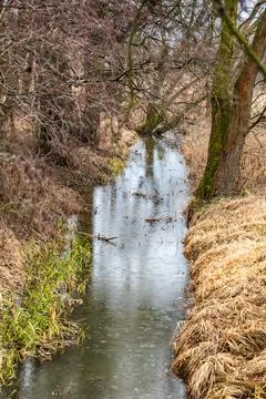 River Flowing Through Winter Meadow Landscape Фото