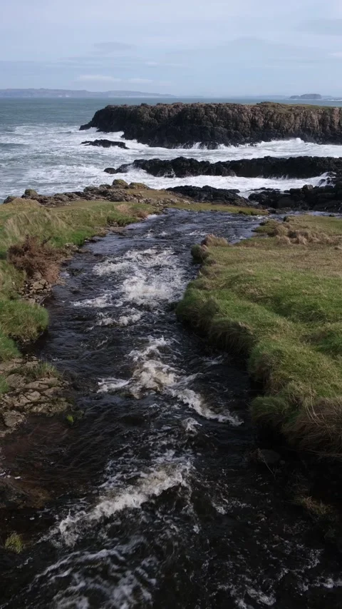 River flowing towards Dunseverick Falls and the Atlantic Ocean below Video stock 303451214