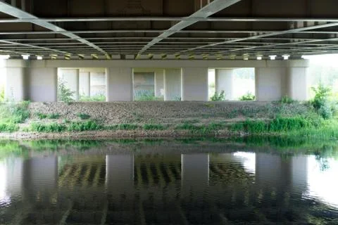 River flowing under bridge with perspective view of concrete columns and shor Stock Photos