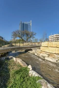River flowing under a bridge with trees buildings and blue sky background Stock Photos