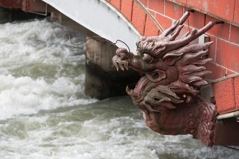 River flowing under a red bridge with a dragon head Stock-Fotos