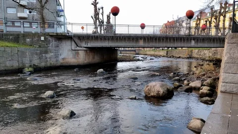 River Flowing Under a Small Town Bridge and People Walking Over Stock-Footage 99624625