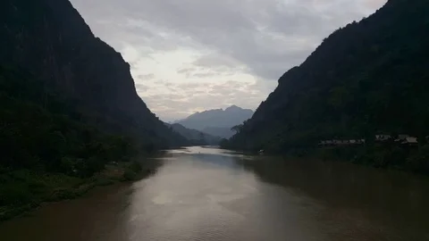 River flows between forest covered mountains, Nong Khiaw village, wooden houses Vidéo 80917080