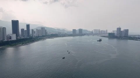 River flows between modern cityscapes with small boats moving gently Видео 345835471