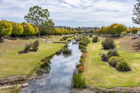 A river flows between two embankments for flood mitigation. Stock Photos