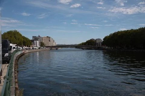 River flows calmly beneath a bright blue sky Stock Photos
