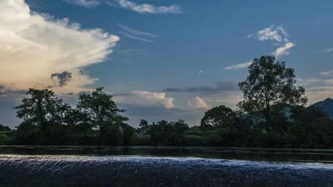 River flows gently beneath a cloudy sky with trees lining the bank Stock Footage 311818286