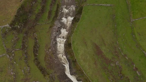 River flows in gorge between fields and falls as waterfall into the sea. Aerial Vidéo 118017133