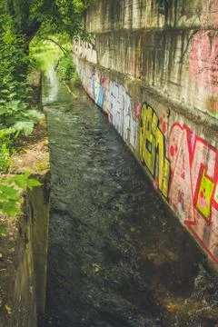 The river flows next to graffiti in thickets Stock Photos