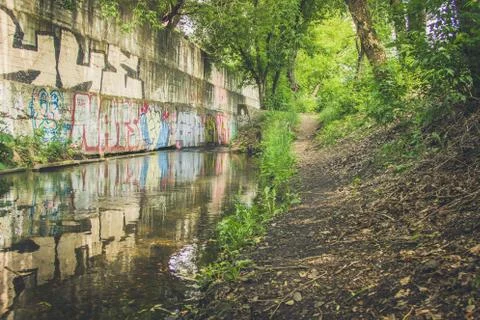 The river flows next to graffiti in thickets Stock Photos