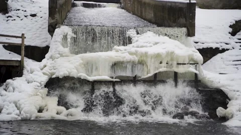 River Flows Over Frozen Waterfall in Slow Motion, Snow Falls on White Winter Day Stock-Footage 151394522