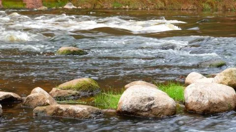 A river flows over rocks in this beautiful scene. Stock Photos