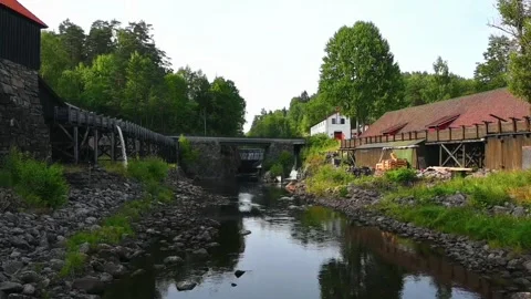 River flows past old buildings in Norway surrounded by trees and rocks duri.. Stock Footage 340211037