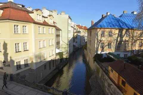 A river flows through a city between two buildings with blue roofs Stock Photos