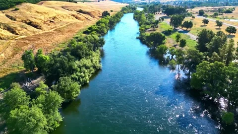 River flows through the desert and green trees on the outskirts during the day Stock Footage 279748847