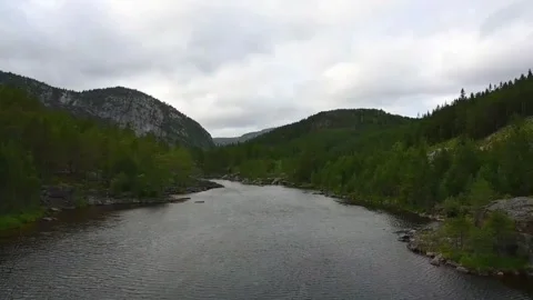 A river flows through green hills under a cloudy sky in Norway during late .. Stock Footage 340202876