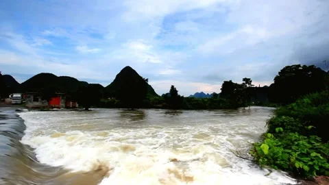 River flows through a lush landscape with mountains and cloudy sky Stock Footage 311817149
