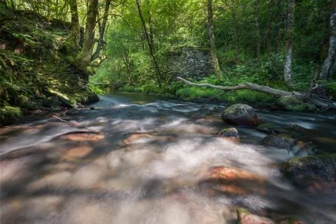 A river flows through the remaining pillars of an old collapsed bridge Stock Photos