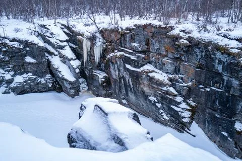 A river flows through a snow-covered canyon, surrounded by icy cliffs. Abis.. Stock Photos