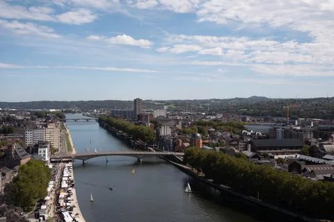 River flows through urban landscape under partly cloudy sky Stock Photos