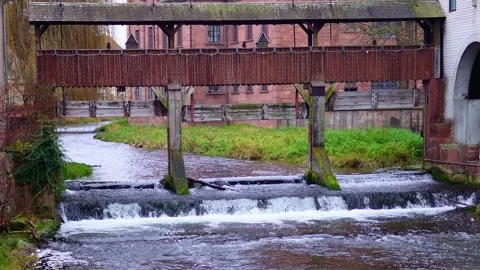A river flows through which an old wooden bridge with a roof passes. Stock Footage 299024313