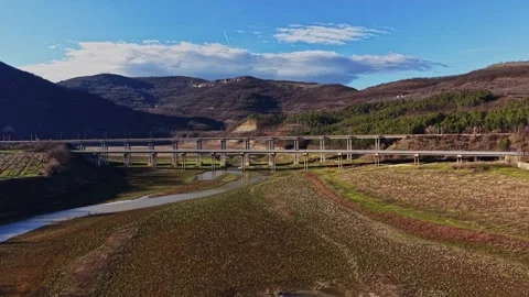 River flows under a bridge with mountains in the background and blue sky Stock Footage 336547073