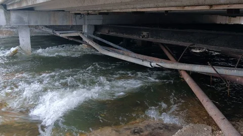 River flows under a bridge with old pipes in the city. Stock Footage 117895458