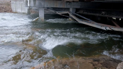 River flows under a bridge with old pipes in the city. Stock Footage 117895865