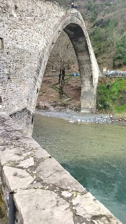 A river flows under a round stone bridge Stock Footage 303759300