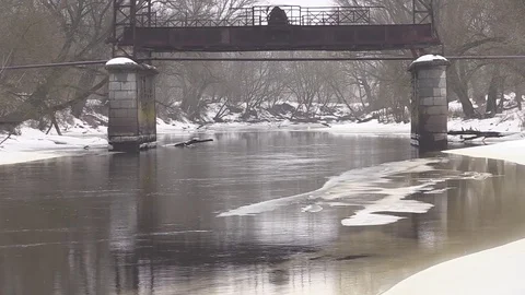 The river flows in winter, snow on the banks of the old destroyed bridge Stock Footage 73684438