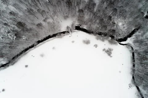 The river flows in winter through a park with trees on which lies snow. Stock Photos