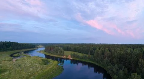 A river with a forest on either side. The water is calm and the sky is a mix  Stock-Fotos