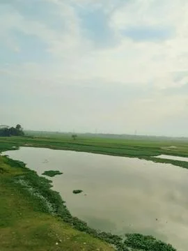 A river with green fields in the background Stock Photos
