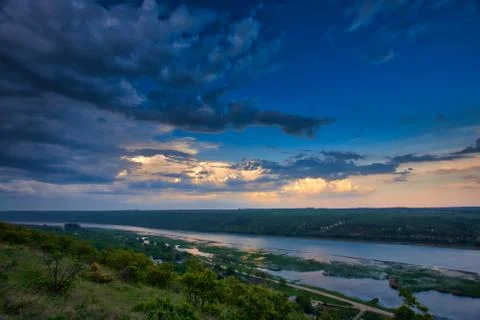 River in green landscape and dramatic clouds with blue sky Foto stock