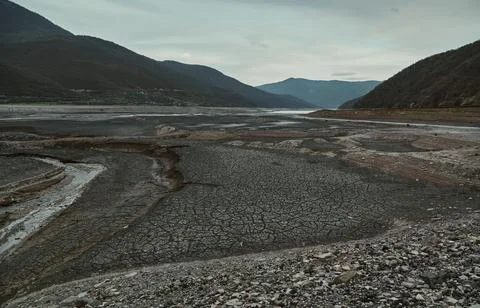 The river grows shallow, the bottom revealed in fresh cracks, the barren valley. Stock Photos