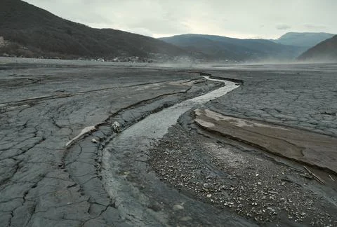 The river grows shallow, the bottom revealed in fresh cracks, the barren valley. Stock Photos