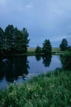 River landscape at evening, dark colours natural landscape with blue lake and Stock Photos