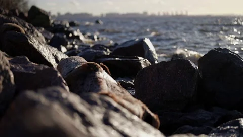 River landscape not far from big city, waves are washing stones on shore Video stock 166802373
