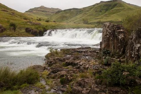 River Lined with Vegetation Flowing Fast over Weir Stock Photos