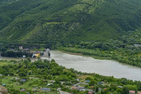 River meander and village below steep green hillside Stock Photos