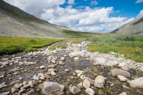 River in mountain valley blue cloudy sky at background. Natural summer landscape Stock Photos