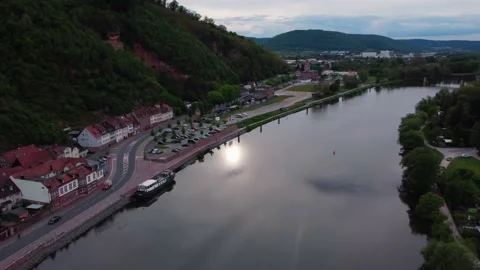 A river next to a town and a green hill from above Stock Footage 154486961