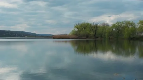 River or lake landscape with reflections of cloudy sky in water. Stock Footage 153993661