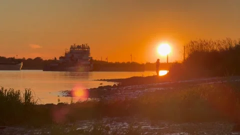 River outside the city in the setting sun, ships and people fishing on the river Stock Footage 279626927