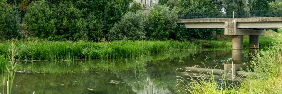 River panorama in summer with slightly cloudy sky and greenery Stockfoto's