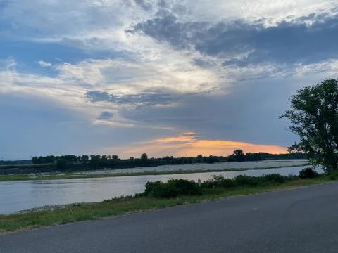 River Po reflecting warm light under a cloudy sky during sunset, showcasing.. Stock Photos